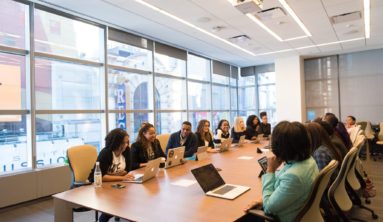 group of people sitting beside rectangular wooden table with laptops