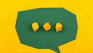 three crumpled yellow papers on green surface surrounded by yellow lined papers