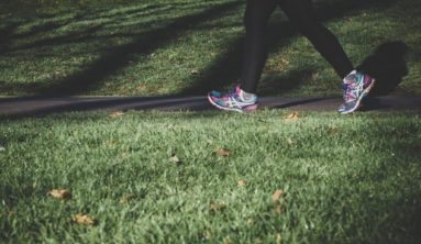 shallow focus photography of person walking on road between grass