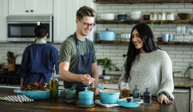 smiling man standing and mixing near woman in kitchen area of the house