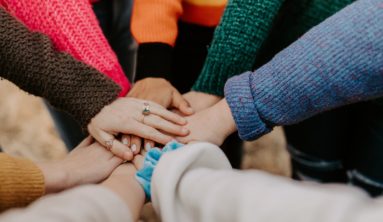 person in red sweater holding babys hand