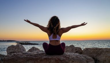 woman sitting on the stone in front of the ocean