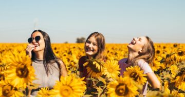 woman in white and black striped shirt standing on yellow sunflower field during daytime